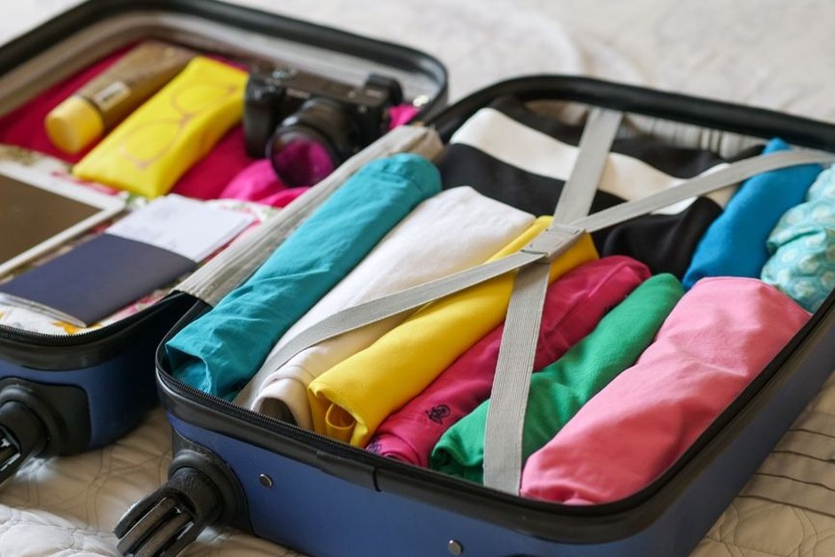 An open carry-on suitcase neatly packed with colorful clothes for a short trip.