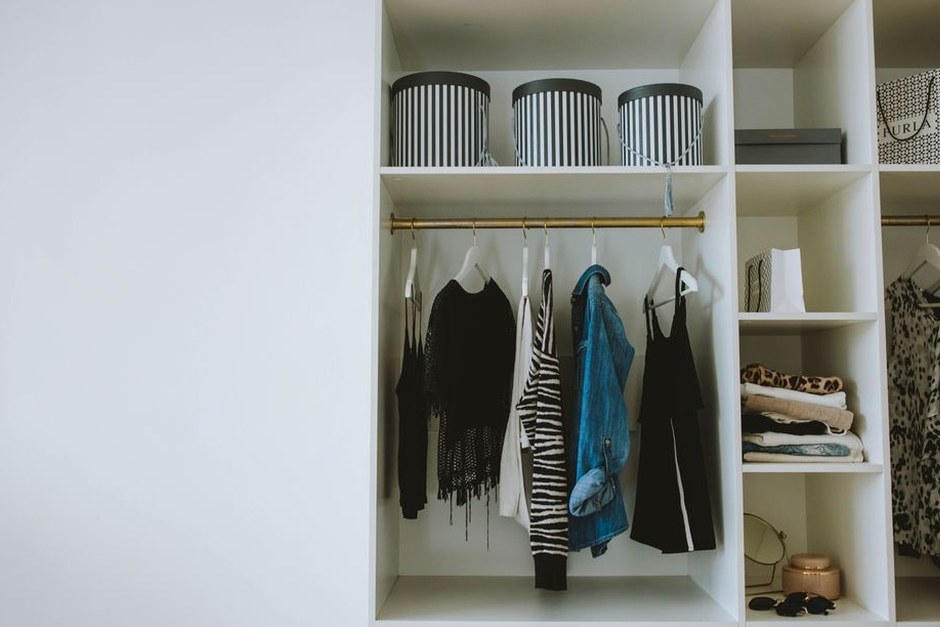 A tidy open wardrobe with a compact selection of clothes and storage boxes.